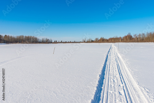 Snowmobile road on a snowy field. Winter landscape on a bright sunny day