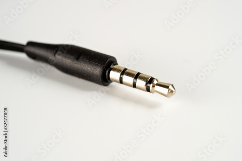3.5 mm plug with a black wire, shot large on a white background. Background for music and computer equipment