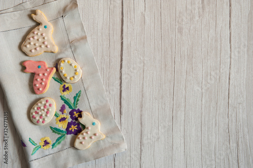 Easter composition. Border of delicious homemade cookies, painted with icing in the form of Easter bunnies and eggs on a light wooden background. Free space.