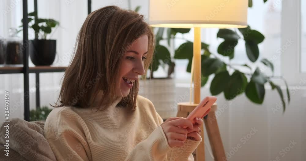 Woman laughing while chatting and flirting using mobile phone at home Woman laughing while chatting and flirting using mobile phone at home