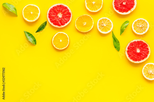 Citrus slices frame - lemons  grapefruits  leaves - on yellow background top-down copy space