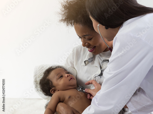 Asian doctor checking on African baby boy in mother's arms. Healthcare for baby concept.