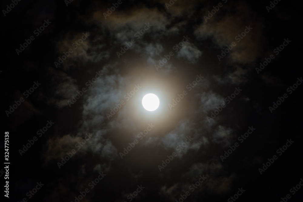 Moon on in the night sky among clouds; natural background of the night sky with the moon