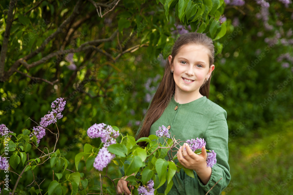 Cute girl has fun in the park with blooming lilacs, enjoys spring and warmth Cute girl has fun in the park with blooming lilacs, enjoys spring and warmth