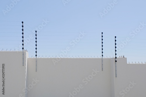 long upright poles holding electric fencing cable on a boundary wall