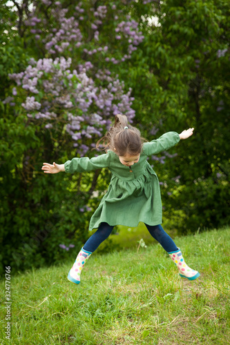 Cute girl has fun in the park with blooming lilacs, enjoys spring and warmth © Olga Gorchichko