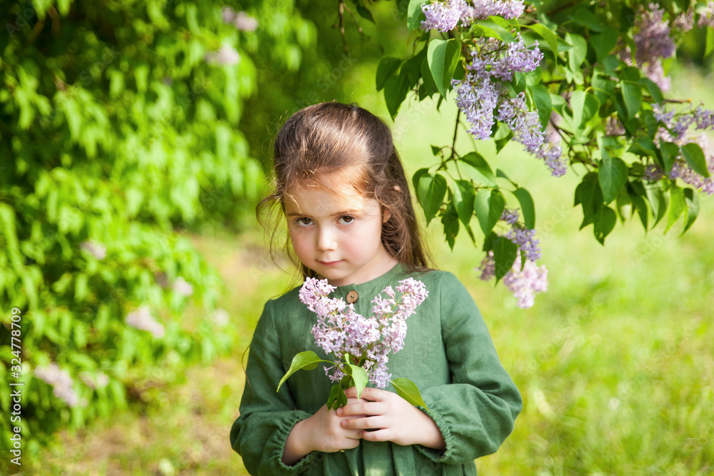 Cute girl has fun in the park with blooming lilacs, enjoys spring and warmth Cute girl has fun in the park with blooming lilacs, enjoys spring and warmth