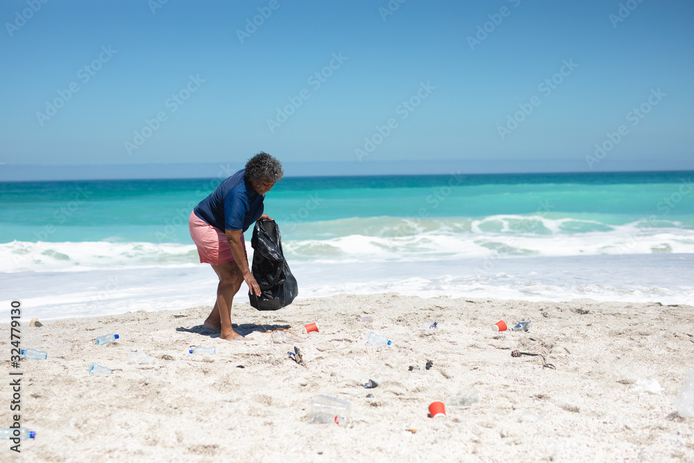 Old woman collecting waste at the beach Old woman collecting waste at the beach