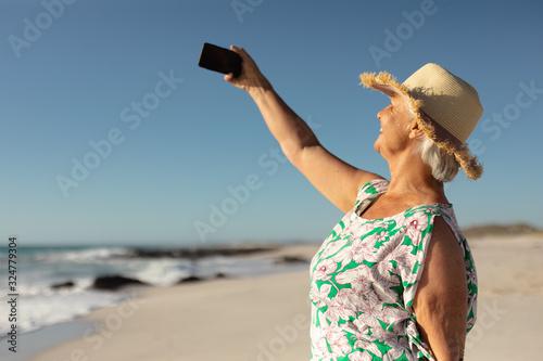 Old woman taking selfies at the beach