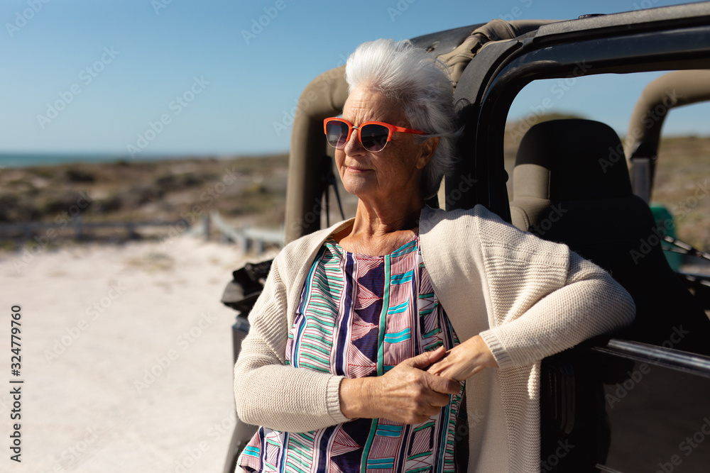 Old woman with a car at the beach
