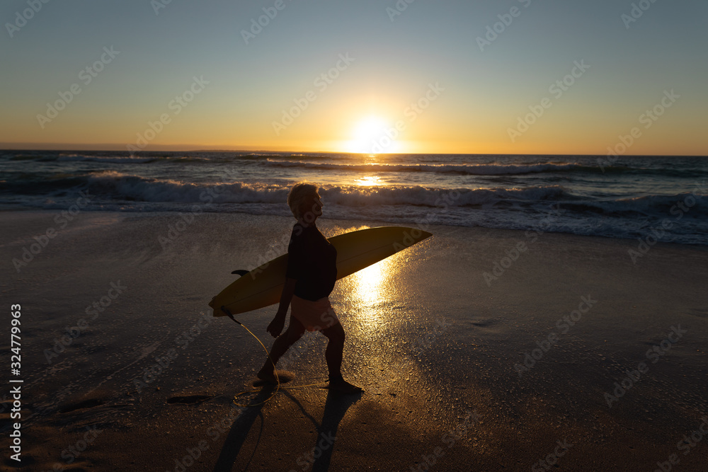 Old woman with a surfboard at the beach