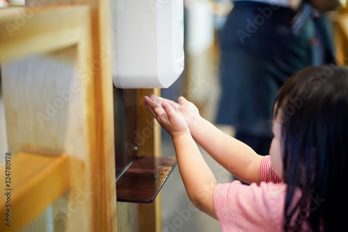 Asian Child girl hand pressing for alcohol gel under the auto sanitizer gel pump dispenser machine and wash Hands applying antibacterial liquid soap, Medical healthcare Skin Care Concept.