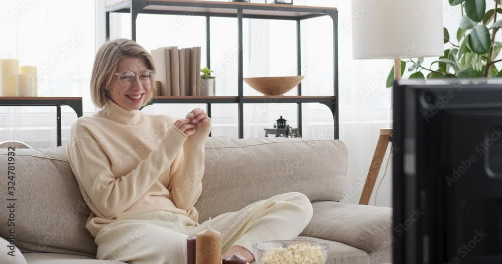Woman laughing while watching funny movie on tv at home Woman laughing while watching funny movie on tv at home