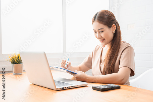Asian young businesswoman working with new project laptop drinking coffee in coffee shop cafe, Analyze plans, papers, hands writing business plan.design notebook technology  startup business concept