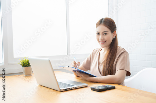 Asian young businesswoman working with new project laptop drinking coffee in coffee shop cafe  Analyze plans  papers  hands writing business plan.design notebook technology  startup business concept