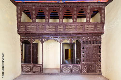 Oriental wooden engraved arabesque decorations with balcony installed in front of open doors inside empty spacious room