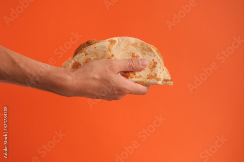 Mexican national food taco or Tatar national food kystyby in hand on an orange background.Food in a tortilla.National food concept photo