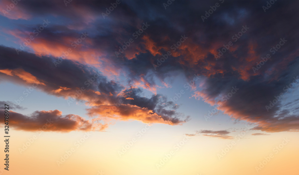 Dramatic sunset background of orange and yellow clouds against a blue sky background.