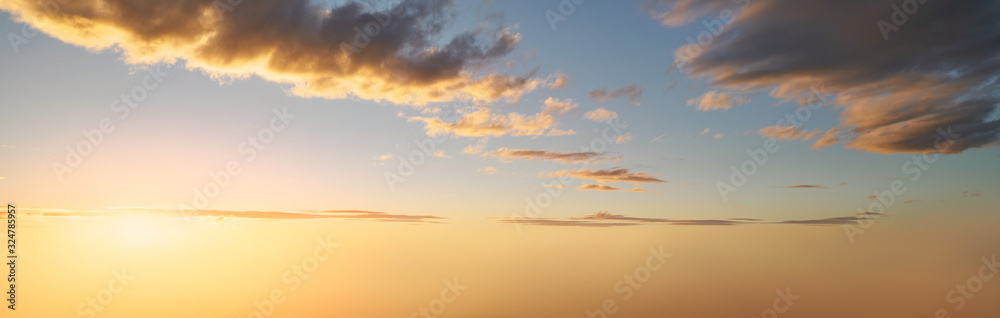 Dramatic sunset background of orange and yellow clouds against a blue sky background. Dramatic sunset background of orange and yellow clouds against a blue sky background.