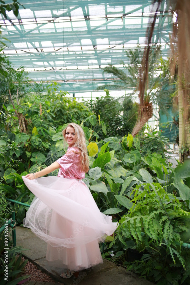 beautiful white long hair girl in a tropical garden walks and dances in a light tulle pink skirt beautiful white long hair girl in a tropical garden walks and dances in a light tulle pink skirt