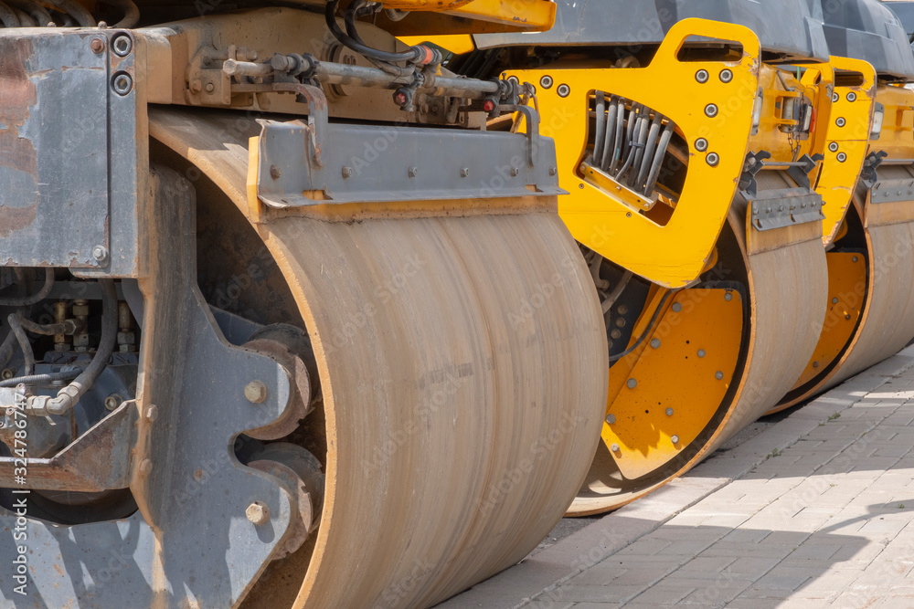Yellow road rollers and an asphalt paver. Yellow road rollers and an asphalt paver.