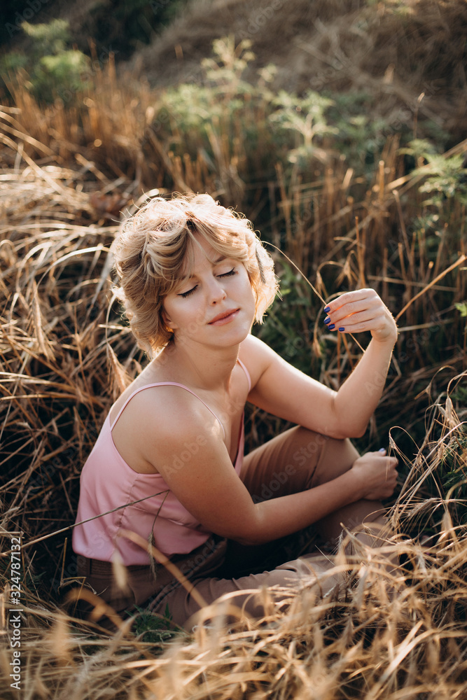 Freedom a happy and beautiful woman with curly hair enjoys the summer sun in a field with wheat on a sunny day. Open space. Freedom a happy and beautiful woman with curly hair enjoys the summer sun in a field with wheat on a sunny day. Open space.