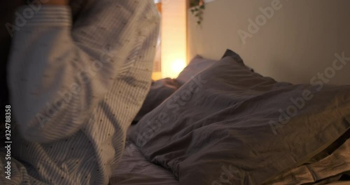 Happy woman going to sleep with quilt on bed at home