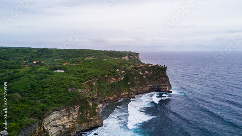 Aerial view of sea rocky coast with surf the waves, Bali, Indonesia, Pura Uluwatu cliff. Waves crushing rocky shore. Seascape, rocks, ocean. Travel concept.