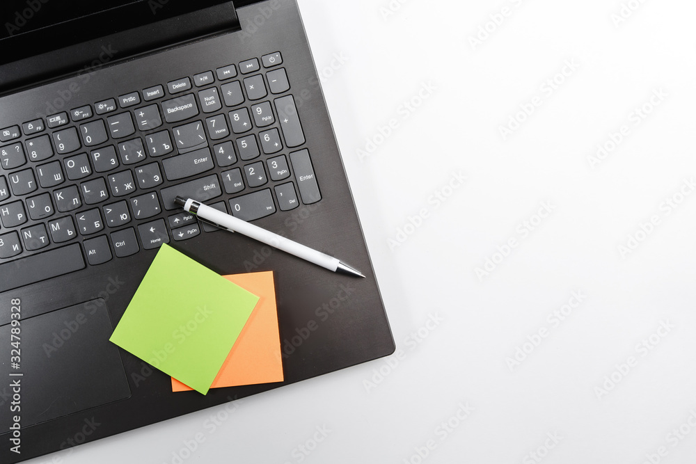 office laptop phone black Notepad open closed pen coffee flower and office colored stickers top view on white background. space for text office laptop phone black Notepad open closed pen coffee flower and office colored stickers top view on white background. space for text