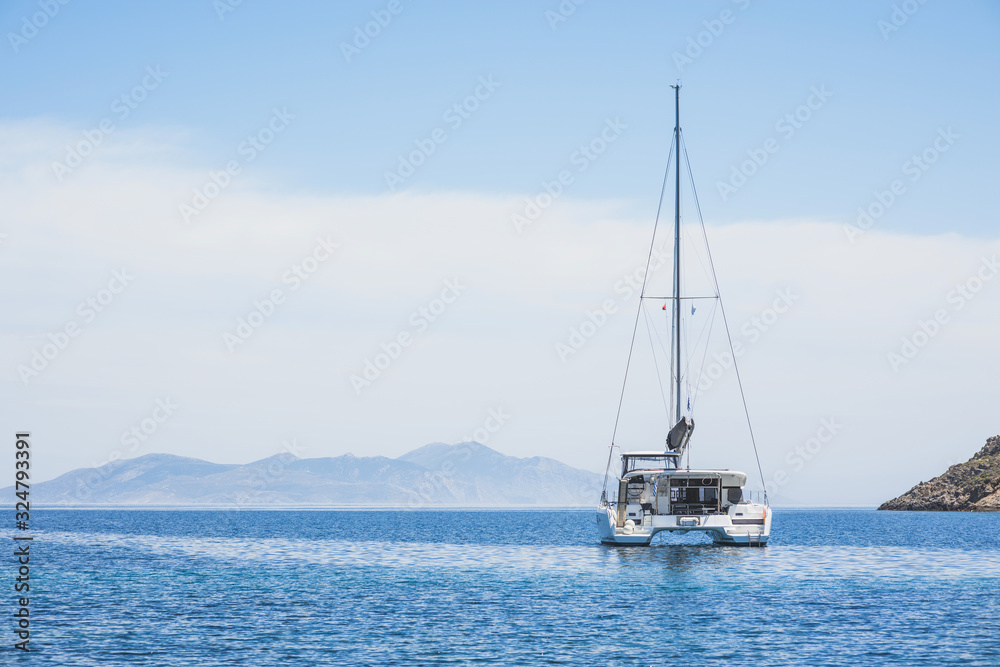Beautiful bay with sailing boat yacht catamaran. Sail boat in a mediterranean sea. Yachting, travel, active lifestyle, summer fun and enjoying life concept Beautiful bay with sailing boat yacht catamaran. Sail boat in a mediterranean sea. Yachting, travel, active lifestyle, summer fun and enjoying life concept