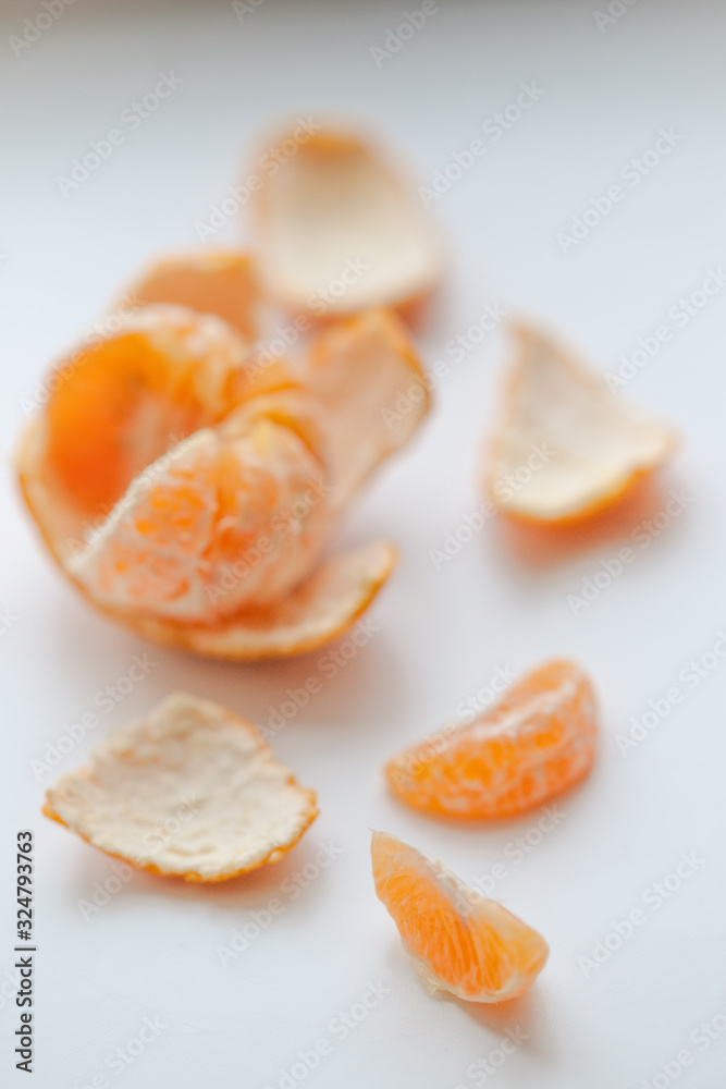 ripe orange mandarin with slices and peel on a white table.