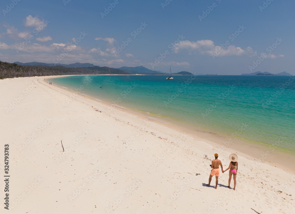 Couple on honeymoon on beach. Whitsundays aerial view, with turquoise ocean, white sand. Dramatic DRONE view from above. Travel, holiday, vacation, paradise. Shot in Whitsundays Islands, Queenstown, A