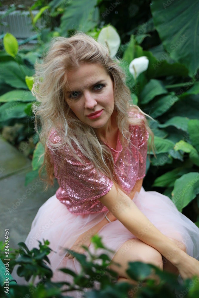 beautiful white long hair girl in a tropical garden in a light tulle pink skirt beautiful white long hair girl in a tropical garden in a light tulle pink skirt