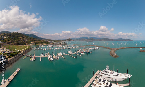 Panoramic marina town aerial. Airlie beach waterfront aerial view. Dramatic DRONE view from above. Marina town with yachts and boats in sea water. Mountain landscape background. Whitsundays Islands photo