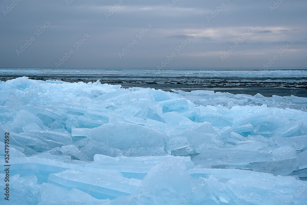 Field of ice hummocks on the frozen lake. Cracked ice on lake in winter season, natural landscape background.