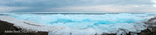 Panoramic landscape of frozen lake. Cracked ice on lake in winter season, natural landscape background.