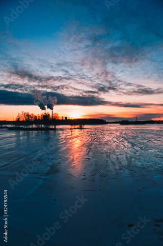 Icy landscape by seashore in sunset.