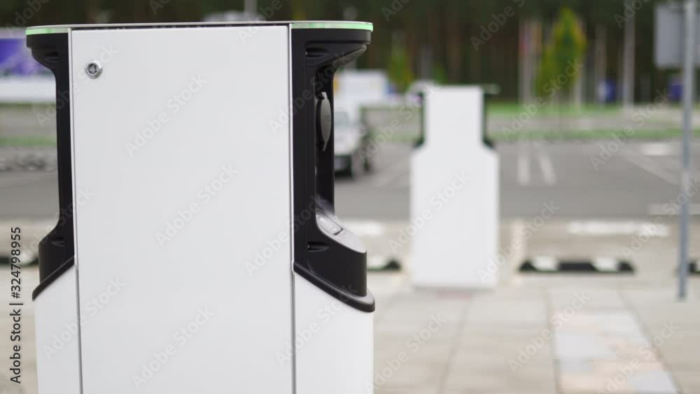 Two electric car chargers at green parking lot. Panning right dolly shot Two electric car chargers at green parking lot. Panning right dolly shot