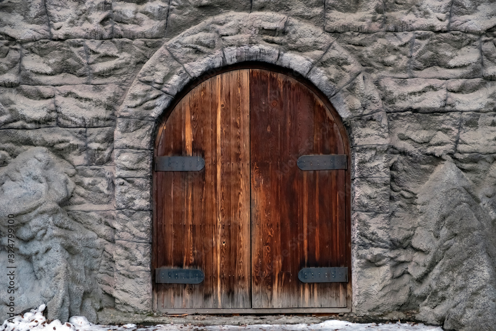 Old castle stone wall with big wooden doors. Retro wooden doors castle rock, great design for any purposes.