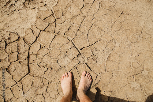 Feet on cracked ground. The concept of heat, drought, vacation.