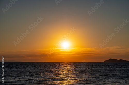 Beautiful sea sunset with island silhouette. Orange sunrise over the sea.