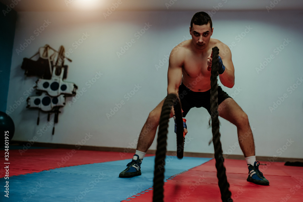 Men with battle rope battle ropes exercise in the fitness gym. CrossFit concept. gym, sport, rope, training, athlete, workout, exercises concept Men with battle rope battle ropes exercise in the fitness gym. CrossFit concept. gym, sport, rope, training, athlete, workout, exercises concept