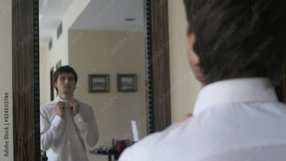 Young handsome man dressing himself in front of mirror. Young handsome man dressing himself in front of mirror.