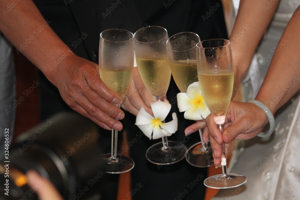 Hands of friends with the bride and groom holding wine glasses in a toast