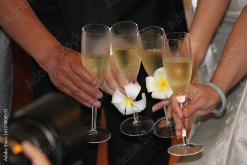 Hands of friends with the bride and groom holding wine glasses in a toast