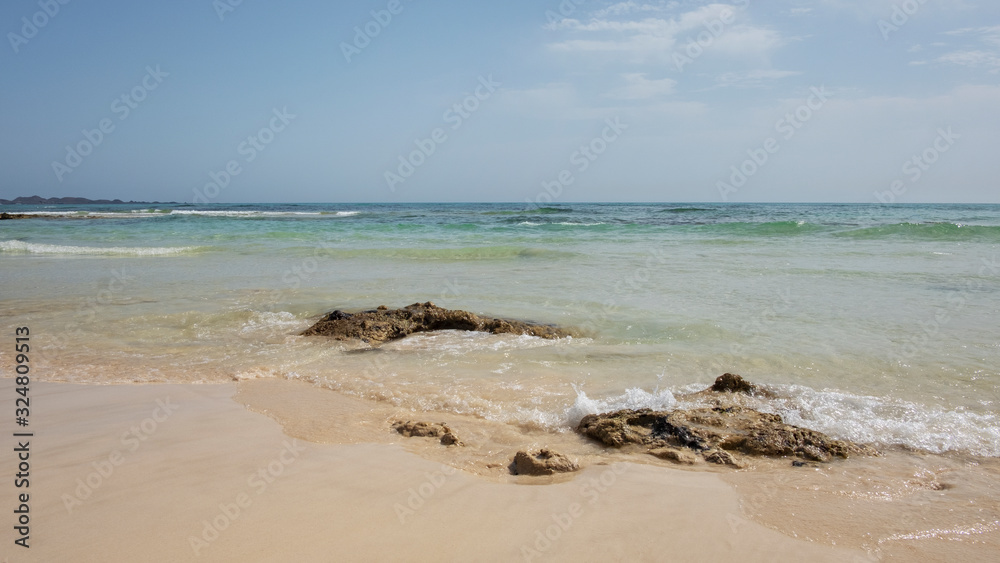 Hot summer views towards the small island of Los Lobos few miles north from Corralejo resort, with calm waves, clear and shallow waters and tropical atmosphere, in Fuerteventura, Canary Islands, Spain Hot summer views towards the small island of Los Lobos few miles north from Corralejo resort, with calm waves, clear and shallow waters and tropical atmosphere, in Fuerteventura, Canary Islands, Spain