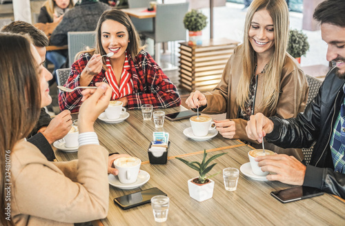 Canvas Print Young friends drinking coffee with milk while doing breakfast in bar bakery shop