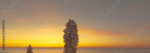 Fototapeta Naklejka Na Ścianę i Meble -  Empilement de galets sur une plage au coucher de soleil, ambiance zen.