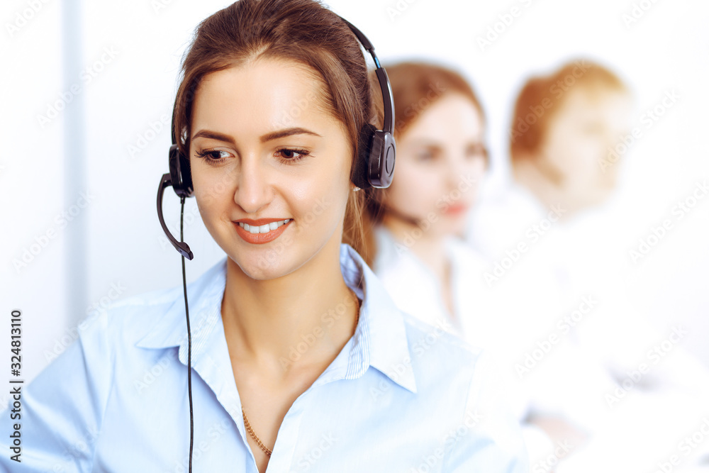 Call center operators. Focus on beautiful business woman using headset in sunny office Call center operators. Focus on beautiful business woman using headset in sunny office