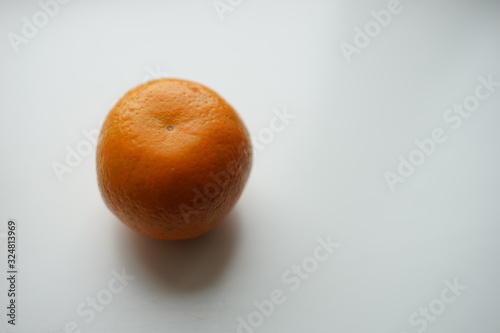 One ripe orange mandarin in a peel on the white table